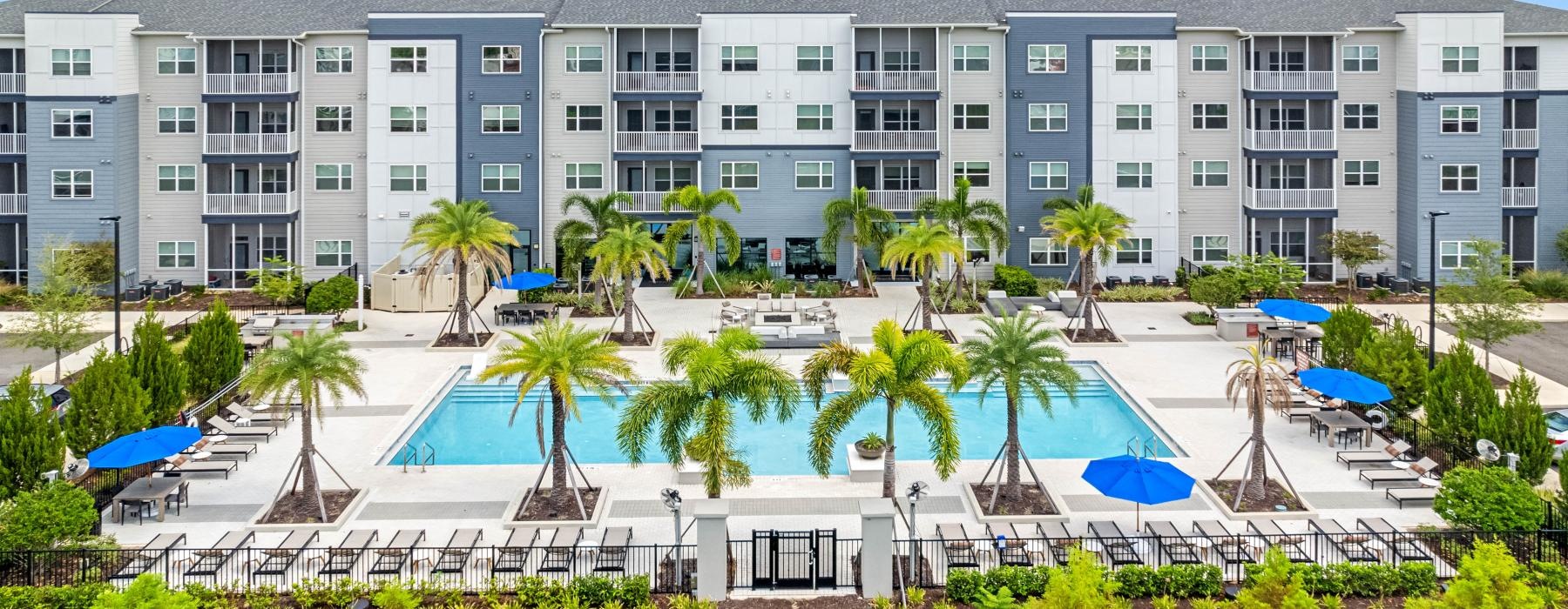 a building with palm trees and umbrellas in front of it