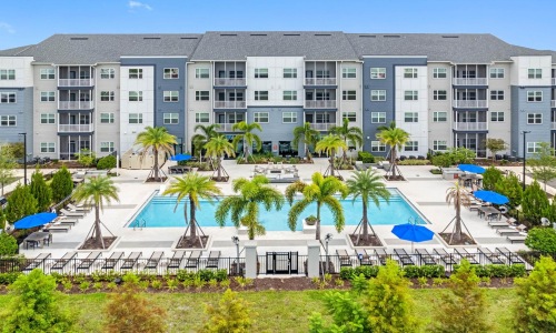 a building with palm trees and umbrellas in front of it