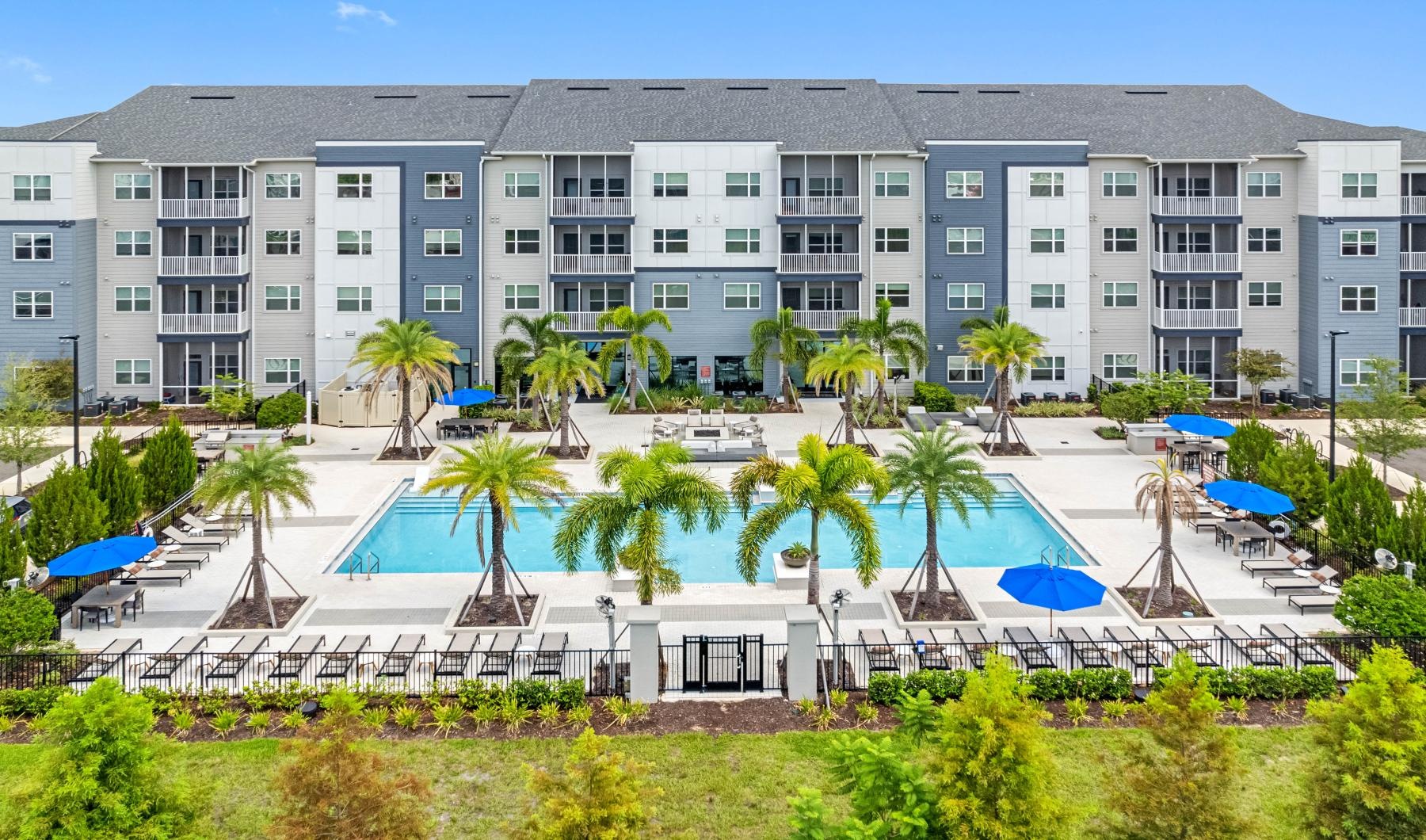 a building with palm trees and umbrellas in front of it