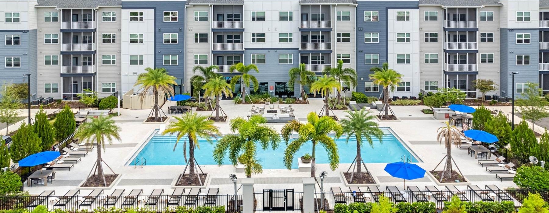 a building with palm trees and umbrellas in front of it